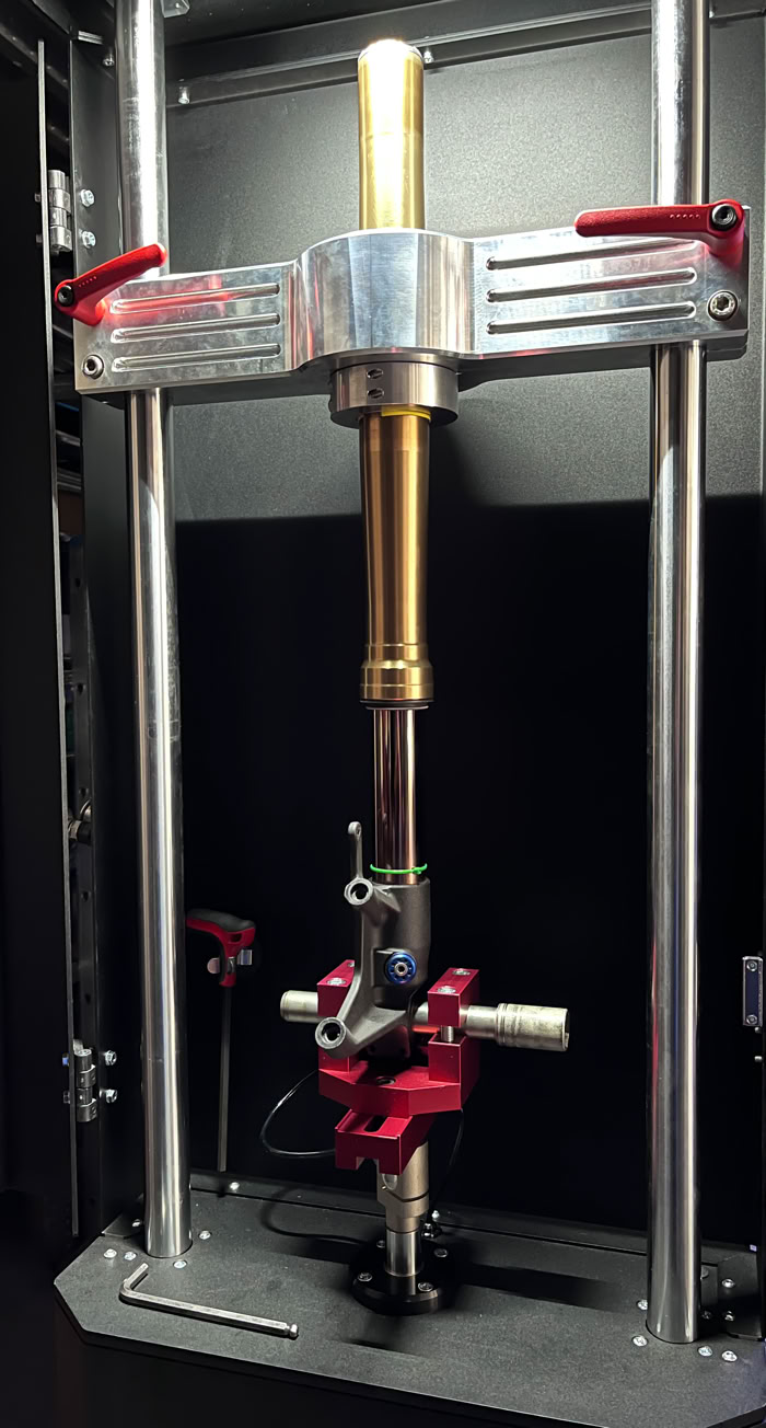 Machine de test de raideur avec deux colonnes verticales et un dispositif central.