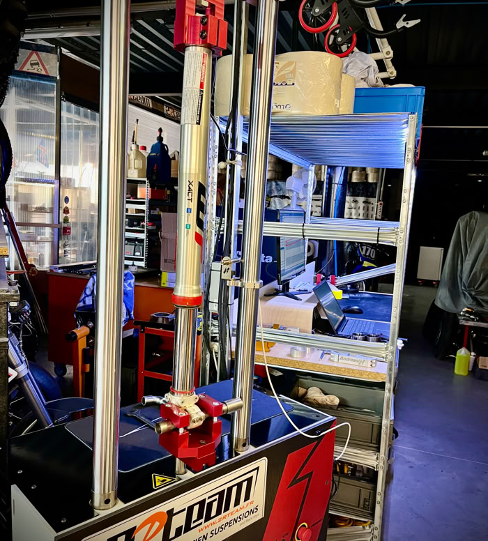 Appareil avec deux cylindres dorés verticaux et une base rectangulaire noire et rouge avec des inscriptions.