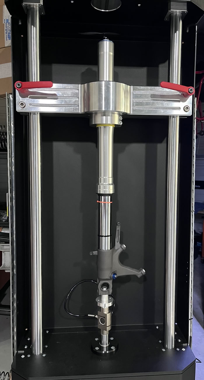 Machine de test de raideur avec deux colonnes verticales et un dispositif central.